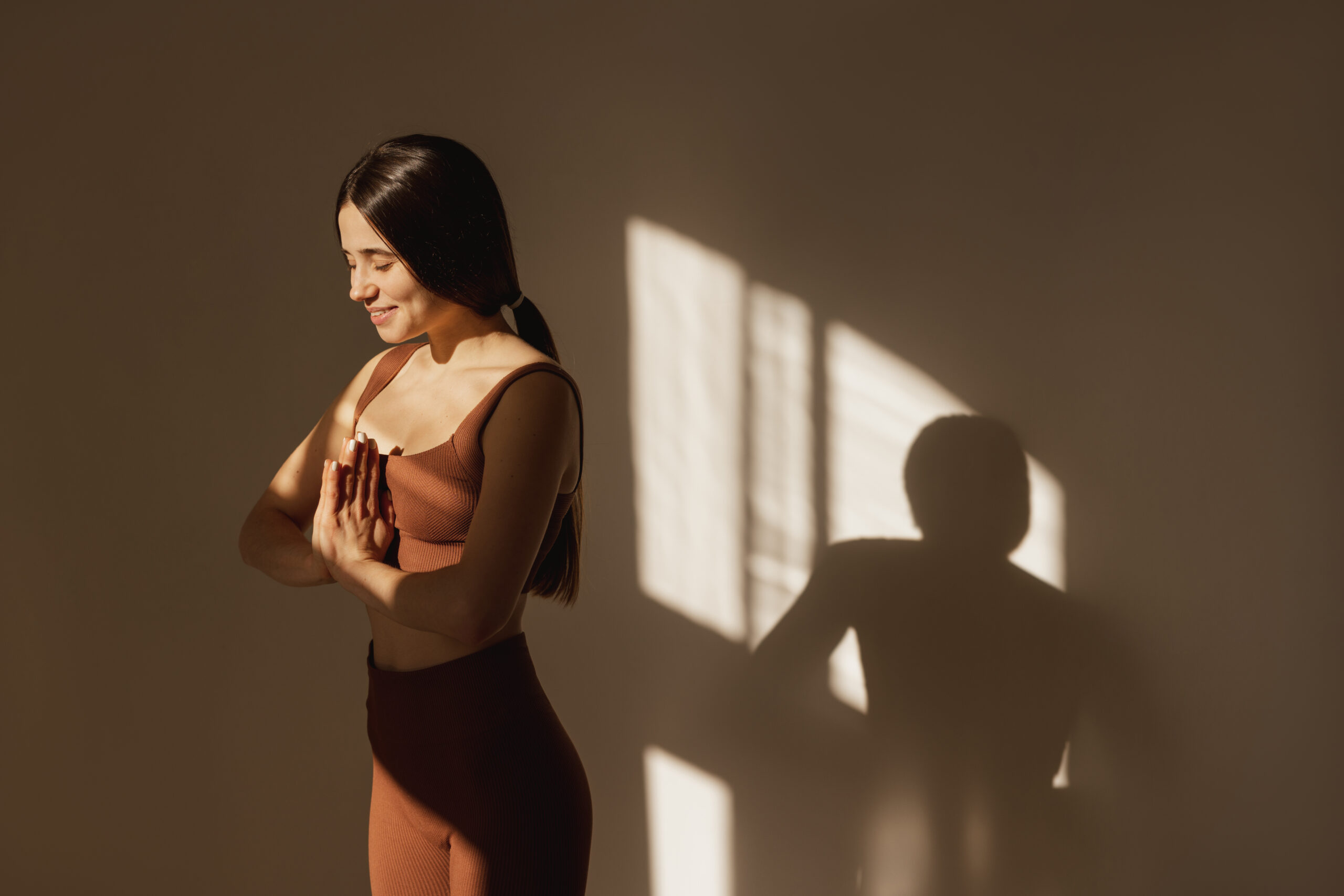 slim-young-caucasian-girl-stands-namaste-yoga-pose-rests-sunlight-morning-home-brunette-top-leggings-meditates-with-her-eyes-closed-fitness-healthy-sport-concept